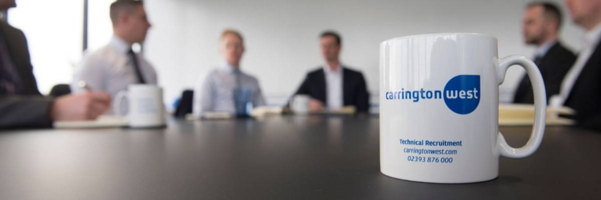 Carrington West branded mug with logo sitting on a boardroom table