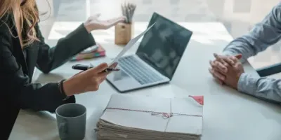 Two people in an interview situation with a laptop in the background showing the importance of being prepared